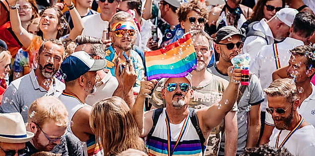 Menschen feiern beim Christopher Street Day in Hamburg mit Regenbogenflagge und queerer Sichtbarkeit