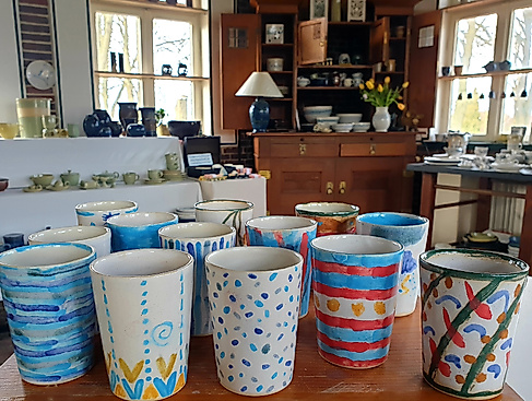 Fantasievoll bemalte Becher, die am Tag der offenen Töpferei 2025 in unserer Werkstatt entstanden sind.