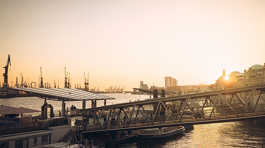 Sonnenuntergang an den Landungsbrücken mit Blick auf Elbe, Schiffe und historische Gebäude im Gegenlicht