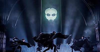 Szenenbild Harry Potter und das verwunschene Kind: Dunkle Atmosphäre, Totenkopf im Hintergrund und Cast beim Tanzen