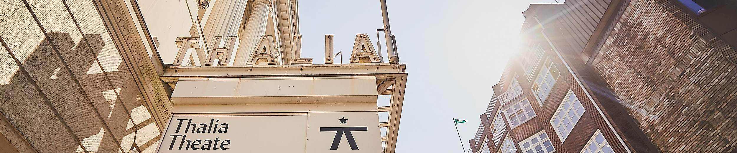 Blick nach oben auf das Thalia Theater Hamburg mit Vordach und Sonne zwischen historischen Fassaden