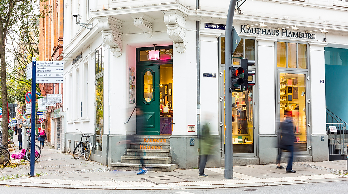 Außenansicht des Kaufhaus-Hamburg in Hamburg-St. Georg mit großer Fensterfront, grüner Tür und Passant:innen