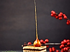 Festlicher Wintercake mit Karamellspitze auf Holzbrett, dekoriert mit Tannenzweigen und roten Beeren