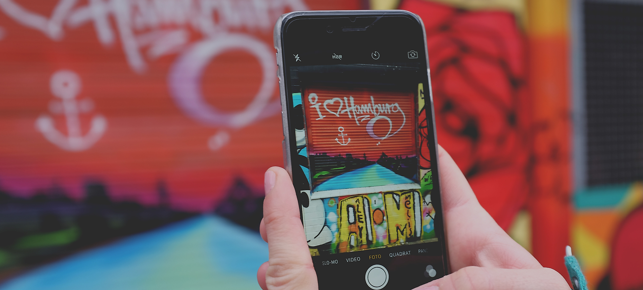 Smartphone fotografiert Hamburg-Graffiti mit Herz und Anker auf bunter Wand in St. Pauli