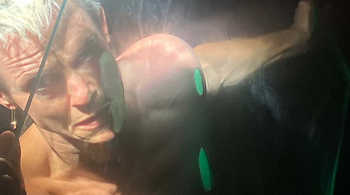 Ausschnitt aus der Perfoprmance Incontrovertible Being von Cassils. Eine Person hält eine Glasscheibe vor sein Gesicht.