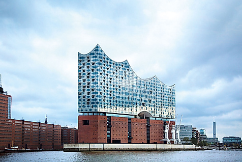 Elbphilharmonie in Hamburg mit gläserner Wellenarchitektur und Backsteinsockel am Wasser