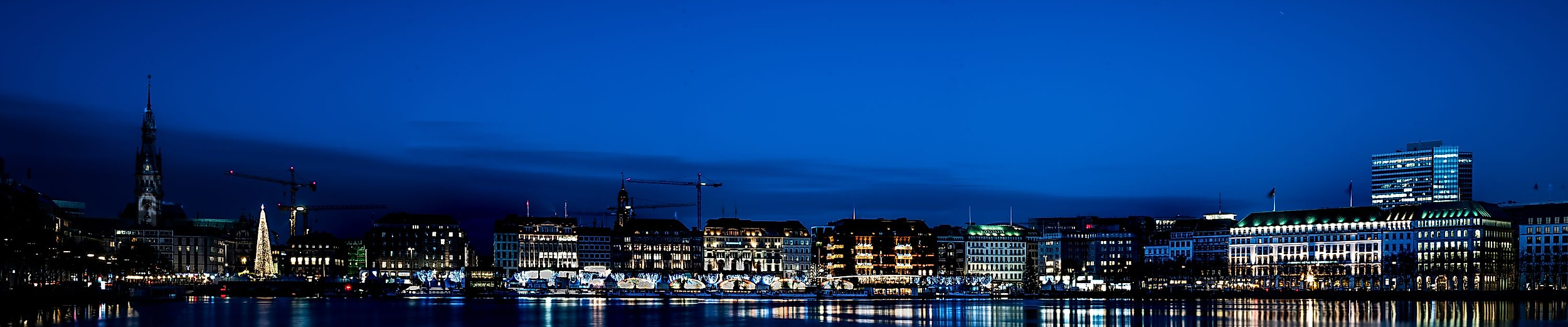 Beleuchtete Binnenalster mit Jungfernstieg und Spiegelungen im Wasser unter klarem Nachthimmel
