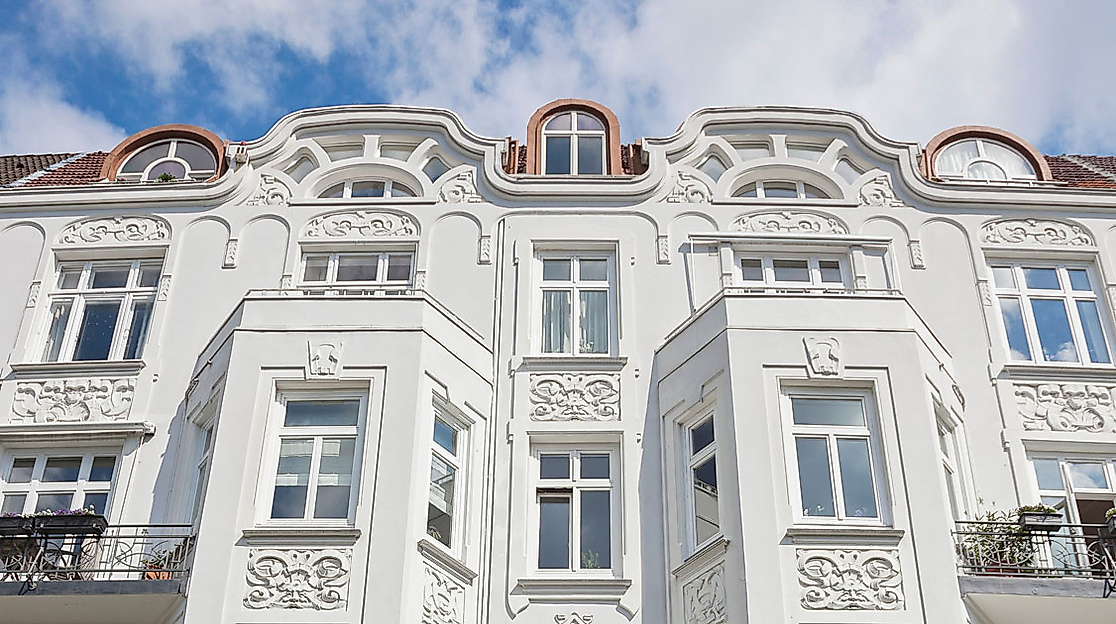 Detailansicht einer weißen Jugendstilfassade mit Ornamenten und Erkern unter blauem Himmel in Hamburg Eppendorf