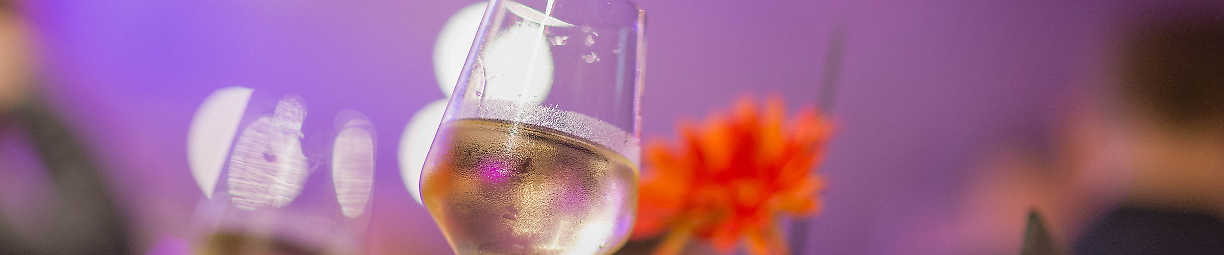 Weingläser und rote Blume auf Stehtisch bei stimmungsvoller Beleuchtung auf dem Winzerfest