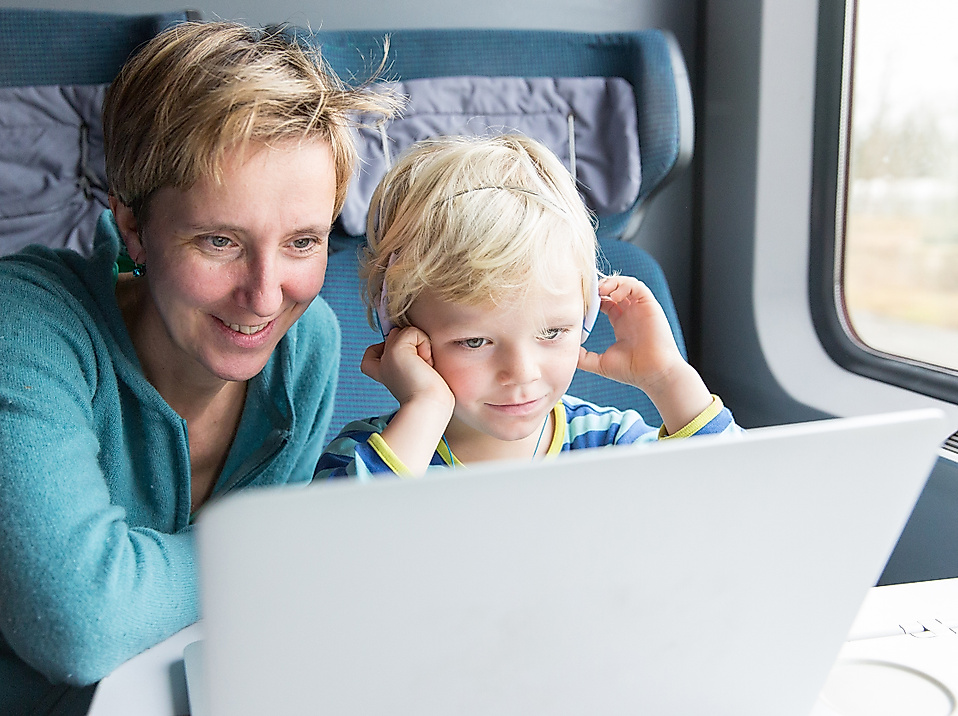 Frau und Kleinkind in der Bahn schauen gemeinsam auf einen Laptop