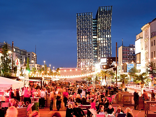 Belebte Abendstimmung auf der Reeperbahn in Hamburg mit Lichterketten, Straßencafés und tanzenden Türmen im Hintergrund