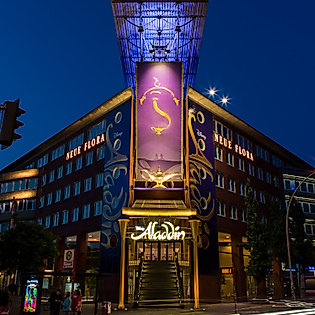 Beleuchtetes Stage Theater Neue Flora in Hamburg bei Nacht mit Banner und gläserner Eingangsfassade