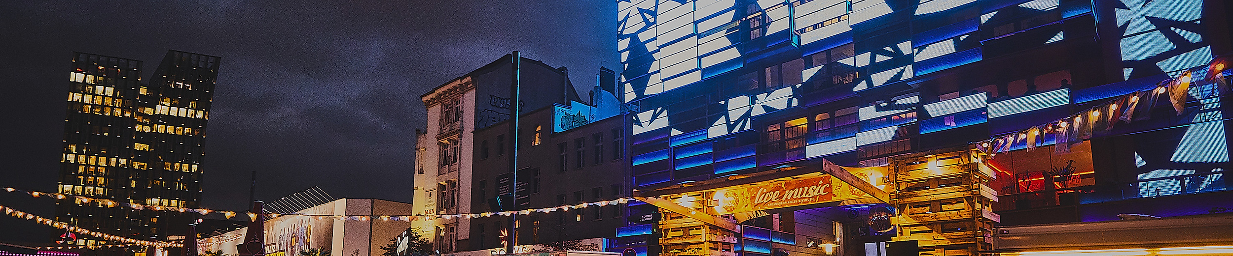 Beleuchtete Fassaden und Street-Food-Stände auf dem Spielbudenplatz in Hamburg-St. Pauli bei Nacht