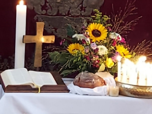 Altar mit Brot, Blumen, Kerze, Kreuz, Bibel