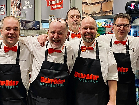 Man sieht die Kolleginnen und Kollegen, die für euch am Abend der Ladies Night 2025 im Schröder Bauzentrum in Itzehoe, die Getränkte ausgeteilt haben. Mit einem weißen Hemd, roter Schleife und einer schwarzen Schröder-Schürze stehen sie auch dieses Jahr wieder bereit und freuen sich auf euch!