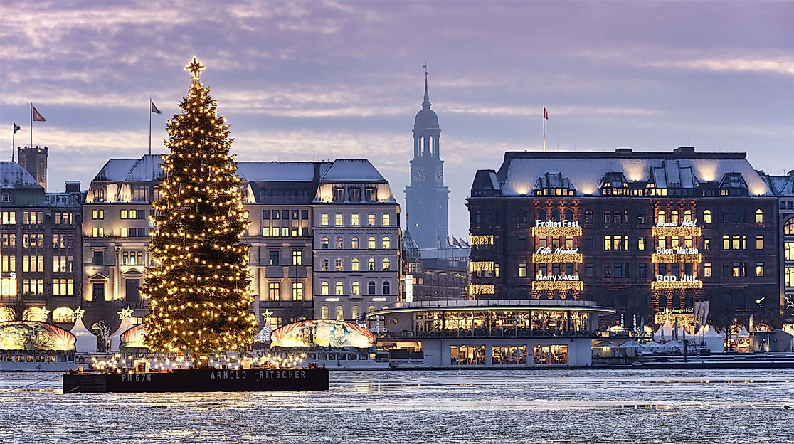 Beleuchteter Weihnachtsbaum schwimmt auf der Alster vor winterlicher Kulisse der Hamburger Altstadt