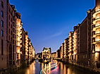 Beleuchtetes Wasserschloss in der Hamburger Speicherstadt bei Nacht, reflektiert im ruhigen Fleet