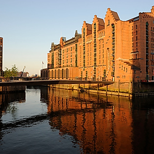 Backsteinfassade des Internationalen Maritimen Museums im Abendlicht mit Spiegelung im Wasser.