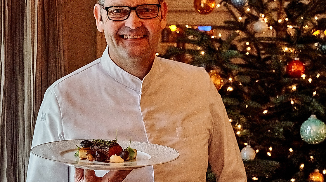 Spitzenkoch Thomas Martin serviert festliches Weihnachtsgericht vor Christbaum im Louis C. Jacob Hamburg