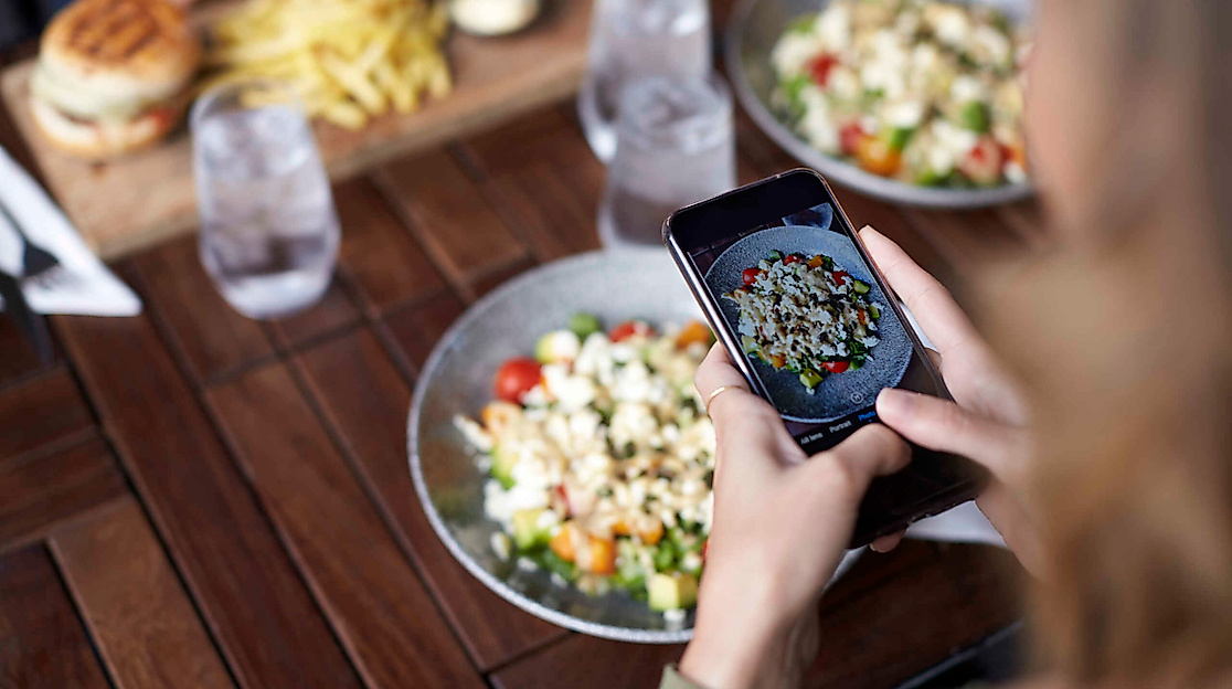 Person fotografiert Essen auf ihrem Teller