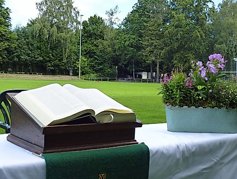 Aufgebauter Altar mit Bibel und Blumenschmuck auf einem Fußballfeld