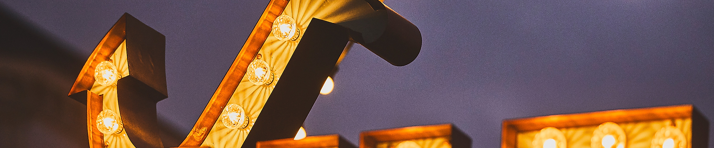 Leuchtbuchstaben „NKF“ mit großer Anker-Skulptur und Lichterkette auf dem Spielbudenplatz bei Nacht