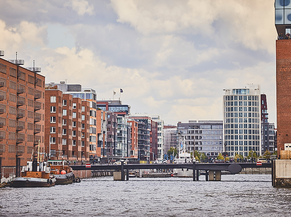 Backsteinfassaden und moderne Gebäude am Fleet in der HafenCity Hamburg mit Brücke im Vordergrund