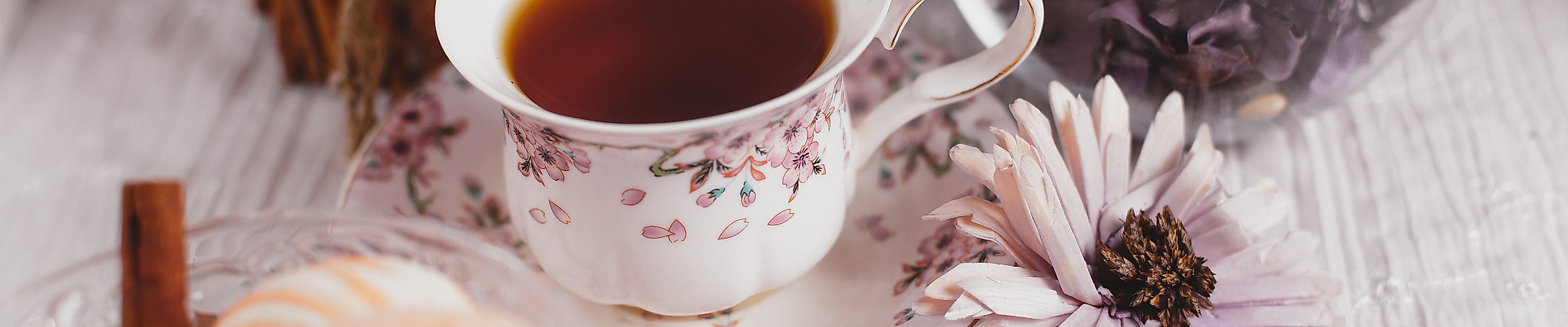 Feine Teetasse mit Schwarztee, Gebäck und Blüte als Hommage an britische Teekultur in Hamburg