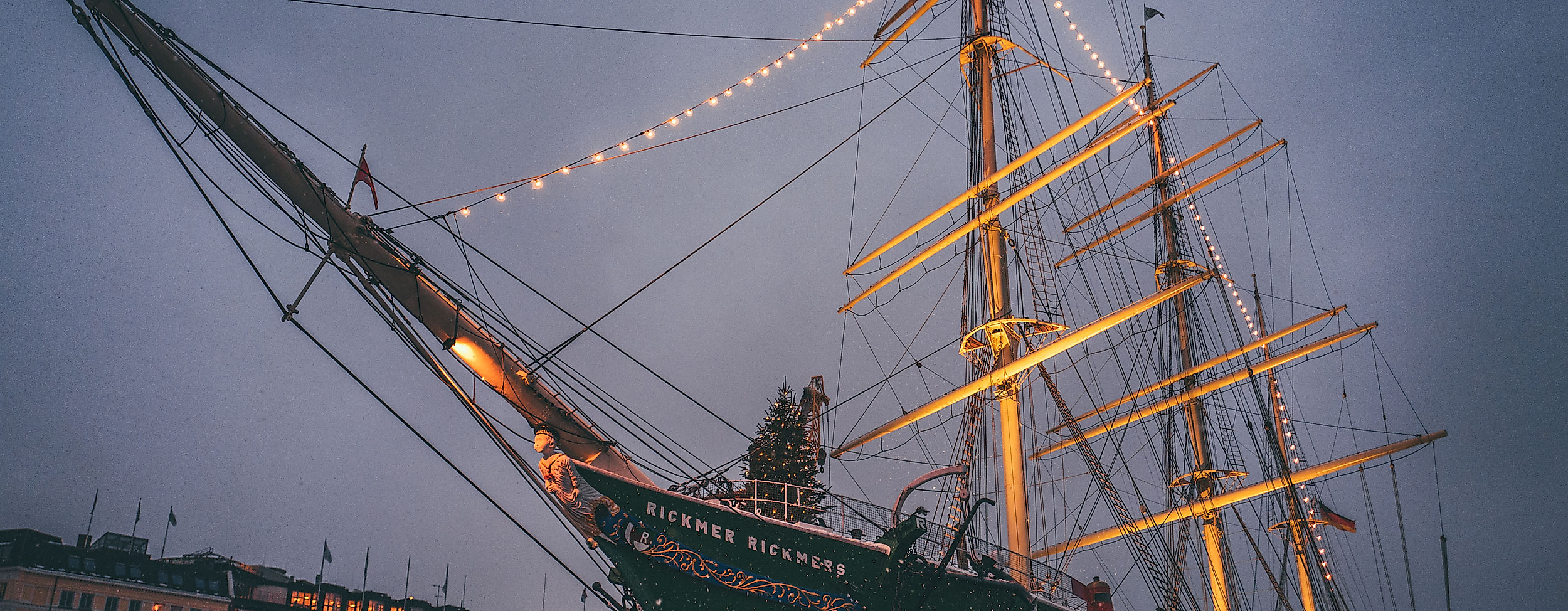 Historic sailing ship festively lit with Christmas lights at dusk in Hamburg’s harbor