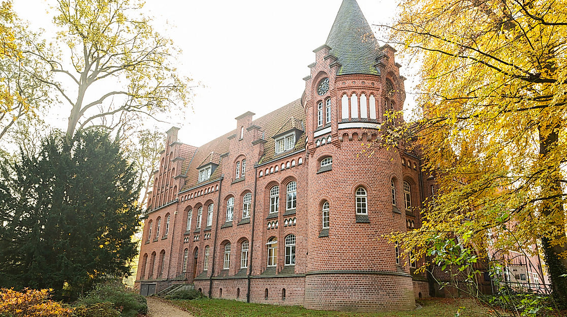 Backsteinbau des Bergedorfer Schloss in Hamburg, umrahmt von herbstlich gefärbten Bäumen und Gartenweg