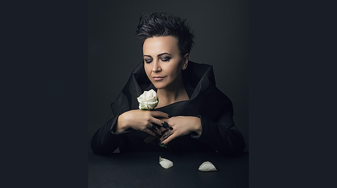 Amira Medunjanin schaut bedächtig auf eine weiße Rose in ihrer Hand.