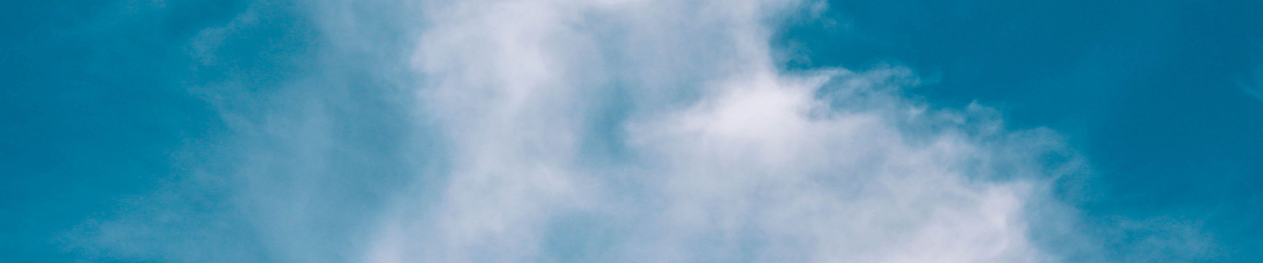 Weiße, federartige Wolke vor blauem Himmel als stimmungsvolle Hintergrundaufnahme.