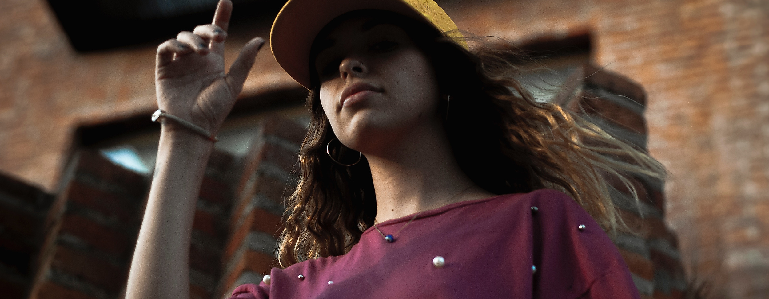 Junge Frau mit Cap und T-Shirt vor Backsteinfassade, Symbol für urbanen Streetstyle in Hamburg