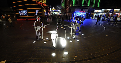 Beleuchtetes Beatles-Platz-Denkmal auf der Reeperbahn bei Nacht mit umliegenden Clubs
