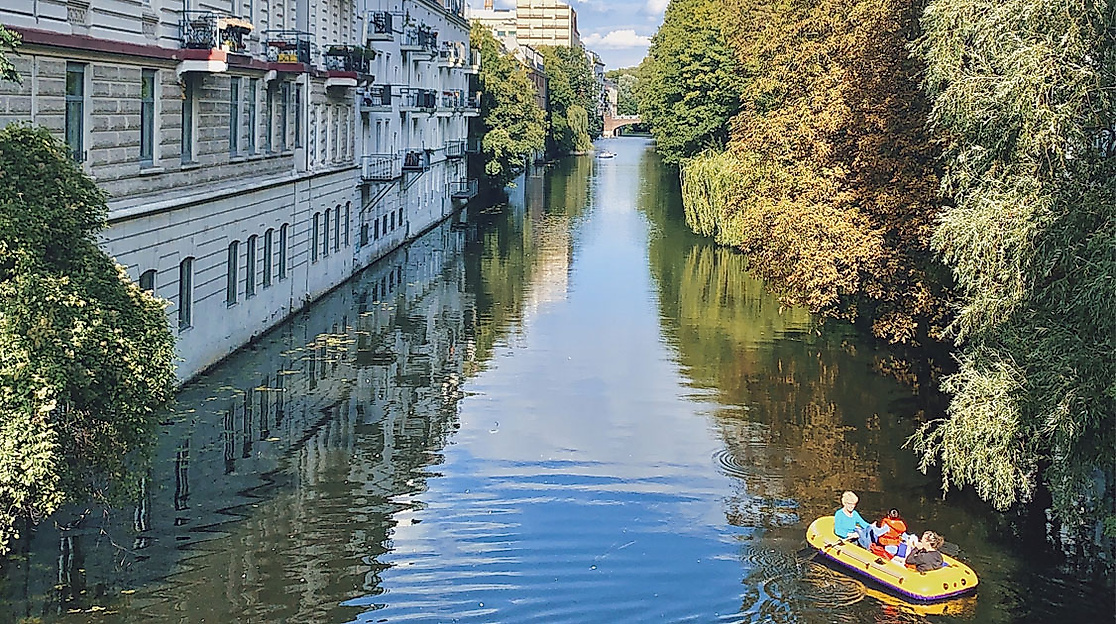 Paddelboot mit zwei Personen auf dem Isebekkanal in Hamburg Eppendorf, flankiert von Häusern und dichtem Grün