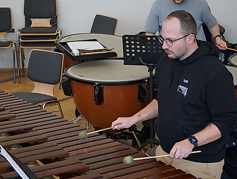 „Rhythmus, der unter die Haut geht: Einblicke in unsere Schlagwerk-Sektion.“

Wenn dieses Instrument erklingt, füllt sich der Saal mit warmer Resonanz. Das Bild zeigt einen unserer Perkussionisten in tiefer Konzentration am Marimbaphon, umgeben von Pauken. Jeder Schlag mit den Schlägeln (Mallets) auf die Holzklangstäbe ist präzises Handwerk und formt den einzigartigen Klangcharakter unseres Orchesters.

Erleben Sie diesen Rhythmus und die klangliche Wucht unseres gesamten Ensembles live und hautnah! Wir laden Sie herzlich zu unserem Konzertabend ein.