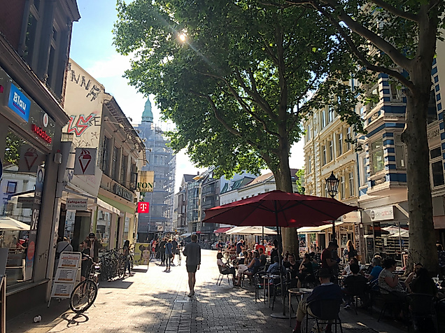 Belebte Ottensener Hauptstraße in Hamburg mit Geschäften, Straßencafés und Passant:innen im Sonnenlicht