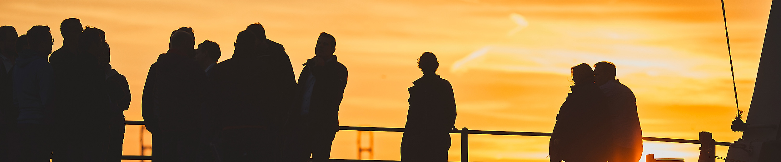 Silhouetten von Menschen  beim Sonnenuntergang an der Hamburger Hafenkante.