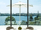 Elegant gedeckter Tisch im The Fontenay mit Panoramablick auf die Alster und weiße Sonnenschirme.