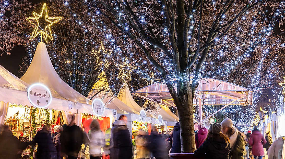 Weihnachtsmarkt in Hamburg mit festlich beleuchteten Zelten und Lichterglanz in den Bäumen bei Nacht.