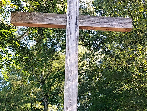 Holzkreuz, dahinter Bäume