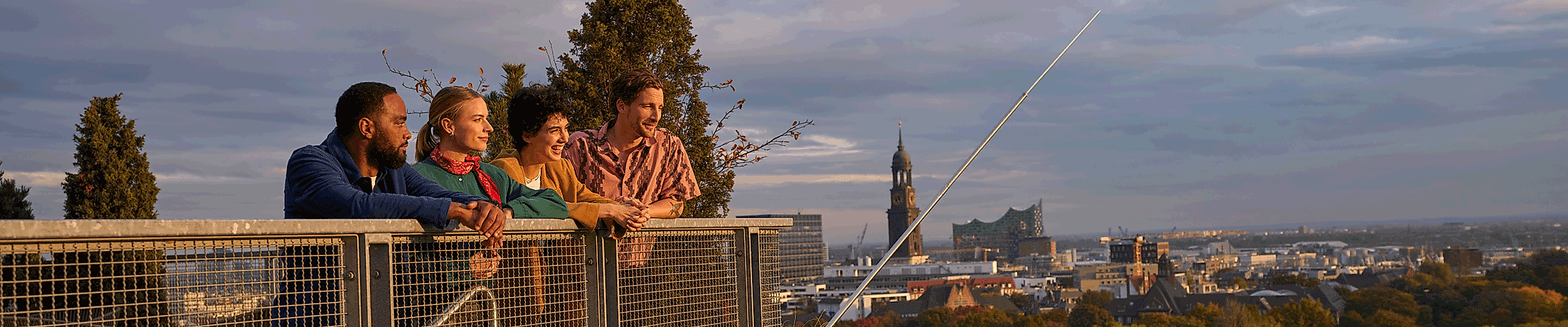 4 junge Menschen dem Hamburger Bunker schauen auf die Skyline Hamburgs