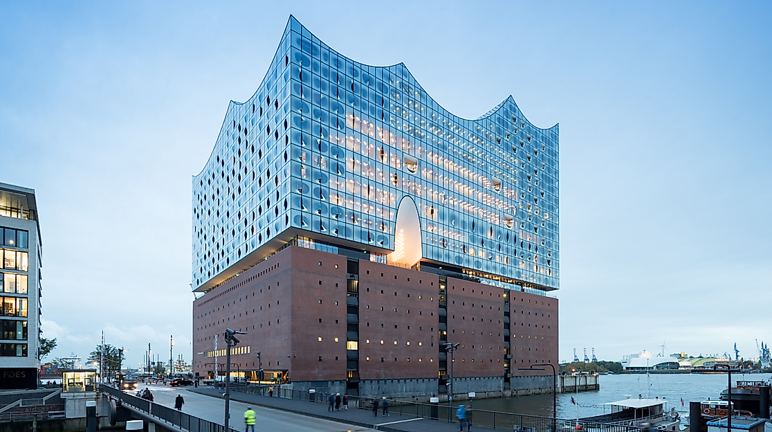 lbphilharmonie bei Dämmerung mit Blick auf Vorplatz und Hafenbecken in Hamburg.