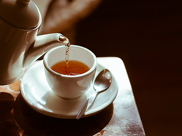 Tee wird in weiße Porzellantasse gegossen, warmes Licht sorgt für gemütliche Atmosphäre bei Tea Tim