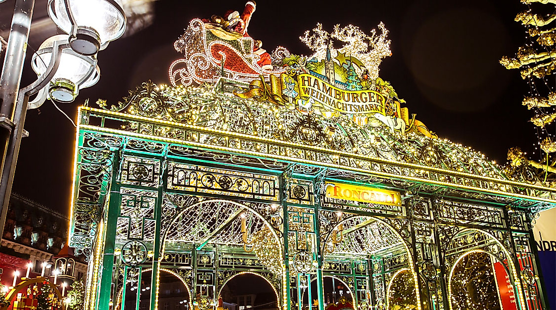 Lichterglänzender Eingang zum Historischen Weihnachtsmarkt am Hamburger Rathaus mit fliegendem Rentierschlitten.