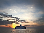 Kreuzfahrtschiff Astor bei Sonnenuntergang auf ruhiger See unter teils bewölktem Himmel