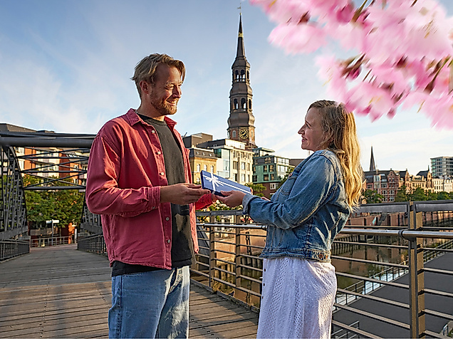 Ein Mann überreicht einer Frau einen Hamburg Gutschein