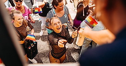 Fröhliche Menschen bei Hamburg Pride erhalten Getränke vom Wagen – queere Sichtbarkeit und Lebensfreude