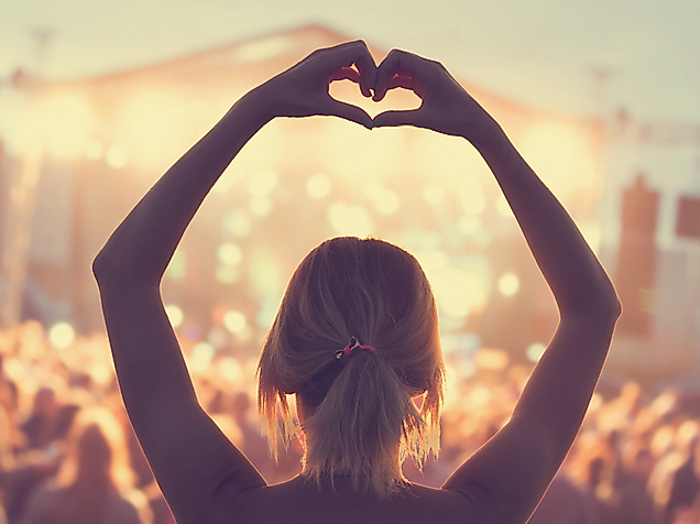 Frau formt mit Händen ein Herz vor beleuchteter Bühne beim Kultursommer