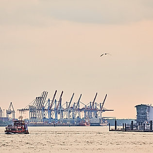 Abendstimmung an den Landungsbrücken mit Blick auf die Elbe, Hafenkräne und pastellfarbenem Himmel.